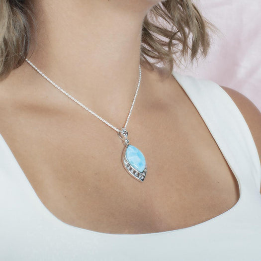 The picture shows a model wearing a 925 sterling silver larimar peacock feather pendant with topaz and aquamarine.