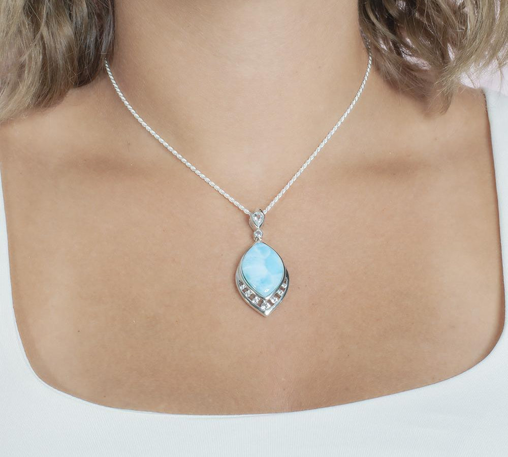 The picture shows a model wearing a 925 sterling silver larimar peacock feather pendant with topaz and aquamarine.