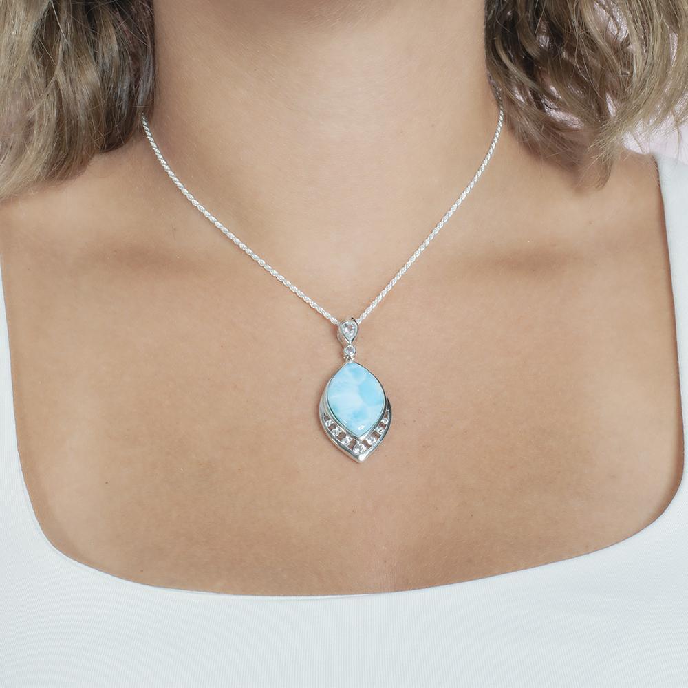 The picture shows a model wearing a 925 sterling silver larimar peacock feather pendant with topaz and aquamarine.