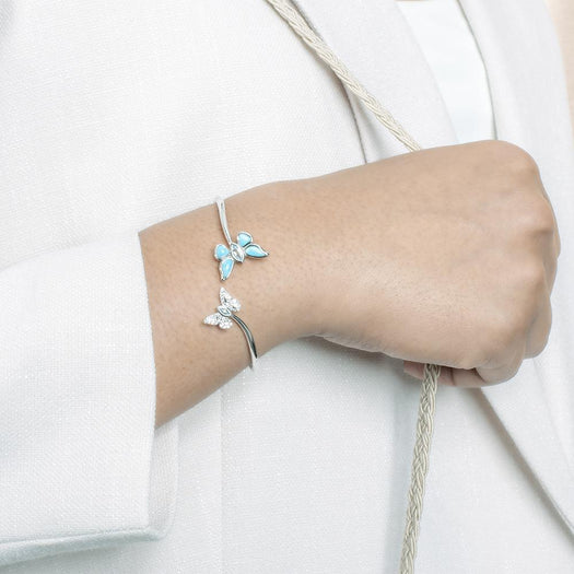 This photo has a model wearing a 925 sterling silver bangle with two butterflies and blue larimar, topaz, and aquamarine gemstones.