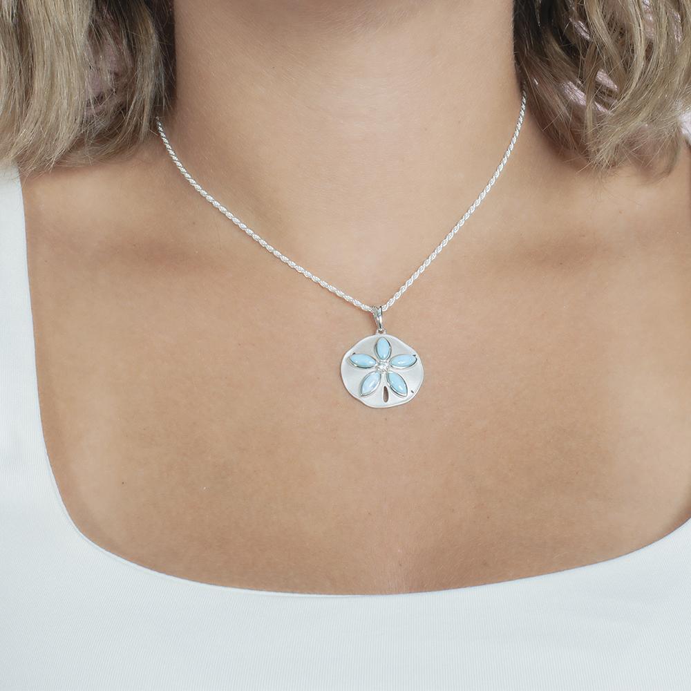The picture shows a model wearing a 925 sterling silver larimar sand dollar pendant with topaz.
