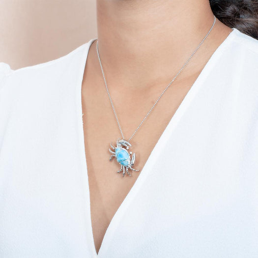 The picture shows a model wearing a 925 sterling silver larimar sand dune blue crab pendant.