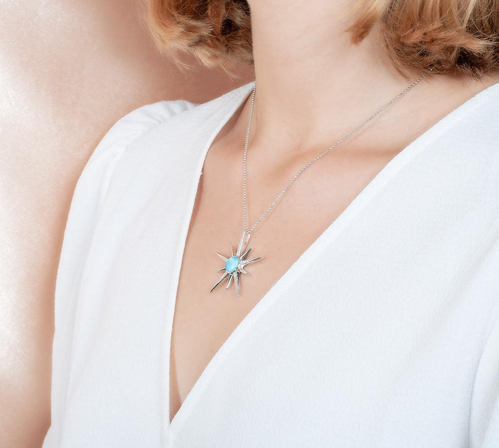 The picture shows a model wearing a 925 sterling silver larimar shooting star pendant.