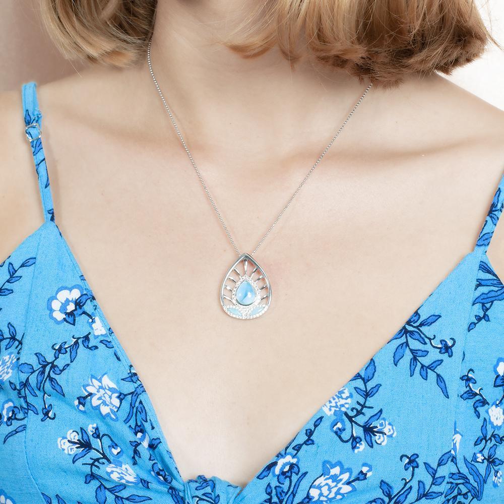 The picture shows a model wearing a 925 sterling silver larimar shrine pendant with cubic zirconia and a blue dress.