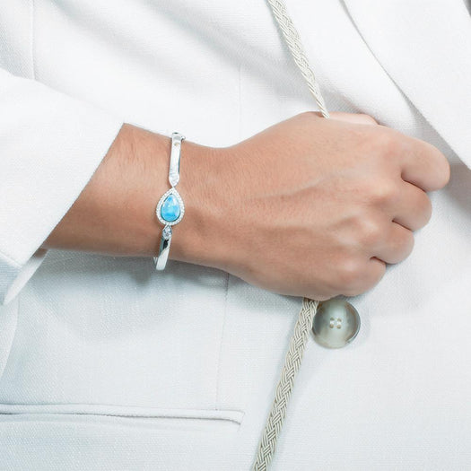 The picture shows a model wearing a 925 sterling silver larimar teardrop bangle with topaz.