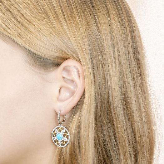 The picture shows a model wearing a 925 sterling silver larimar star lantern lever-back earring with topaz