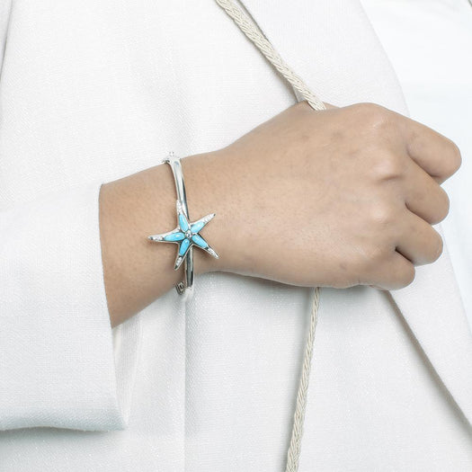 The picture shows a model wearing a 925 sterling silver larimar sea star bangle with topaz.
