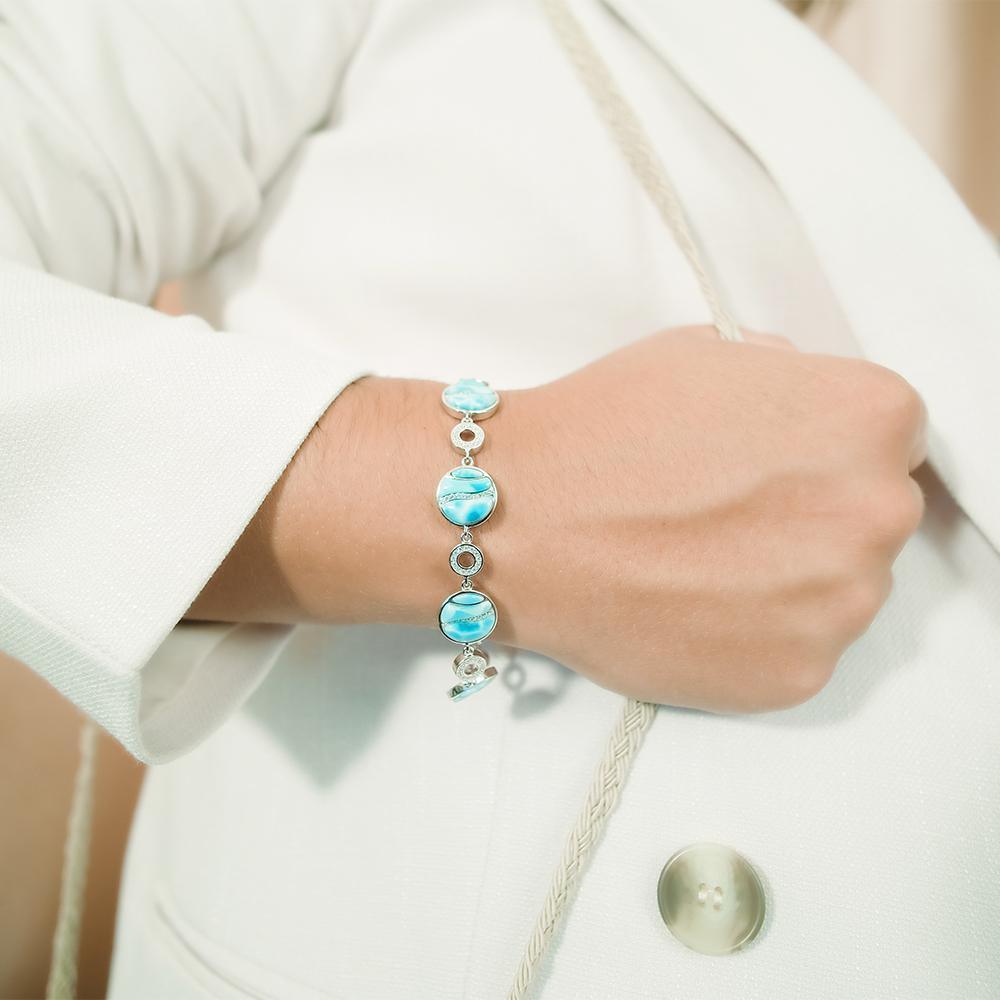 The picture shows a model wearing a 925 sterling silver larimar striped circle bracelet with topaz.