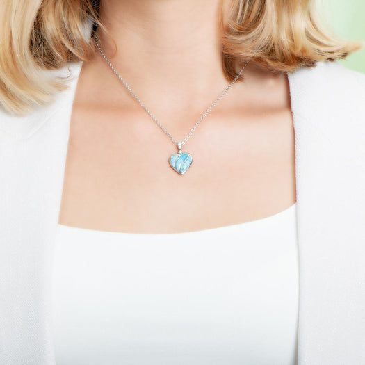 The picture shows a model wearing a 925 sterling silver larimar striped heart pendant with topaz.