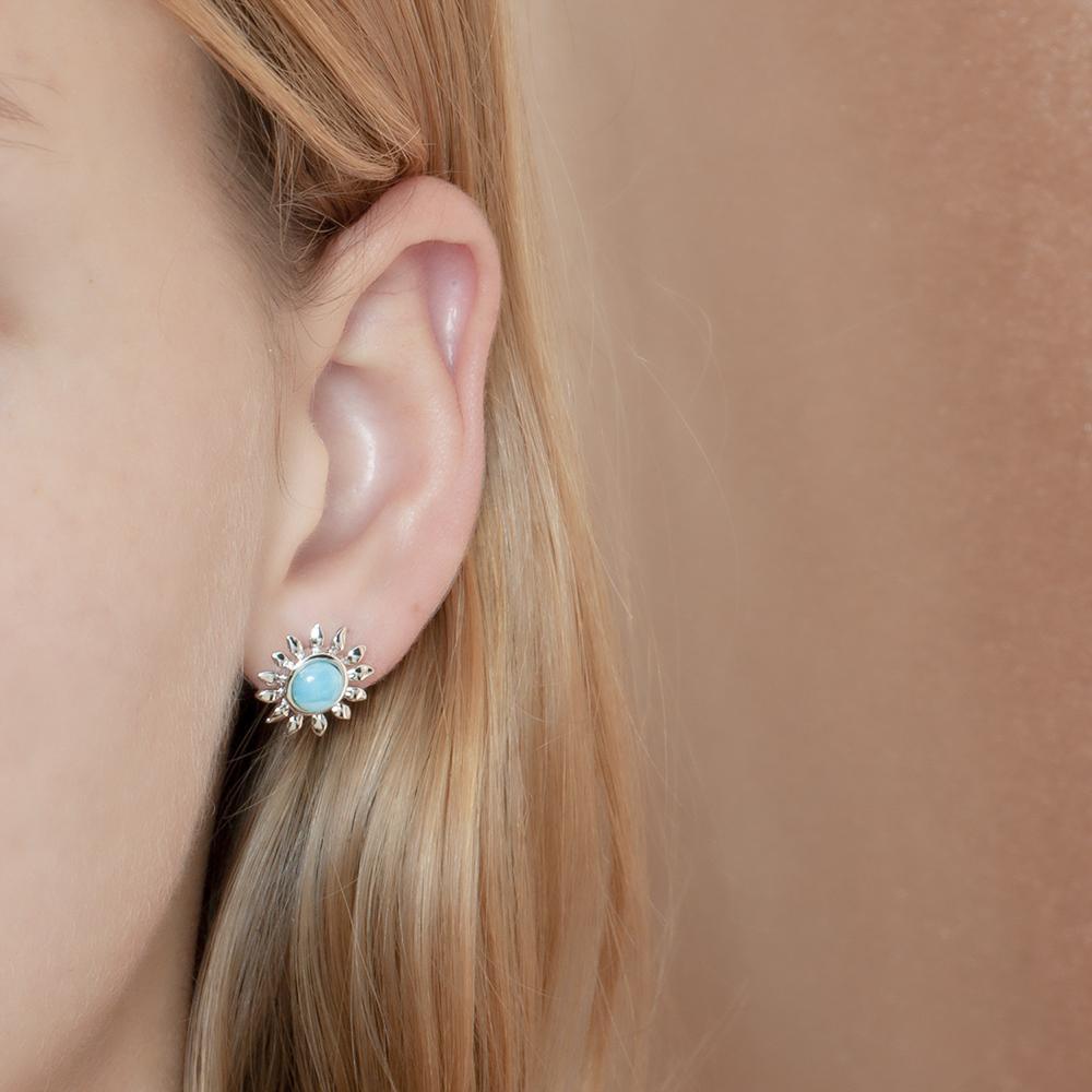 In this photo there is a model wearing a 925 sterling silver sunflower stud earring with a blue larimar gemstones.