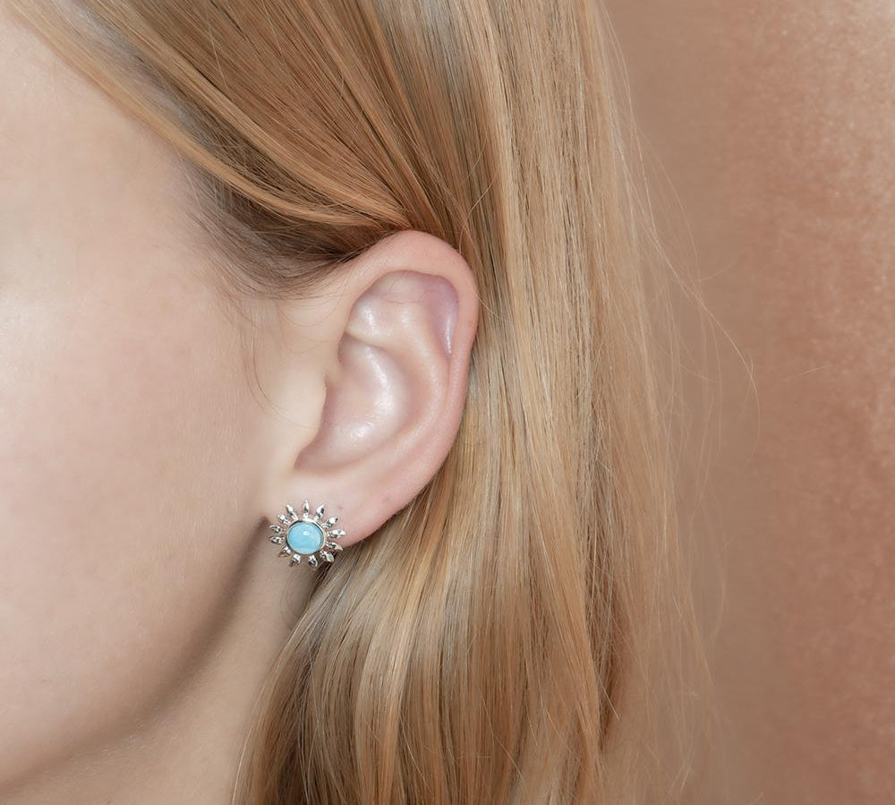 In this photo is a model wearing a 925 sterling silver sunflower stud earring with a blue larimar gemstones.