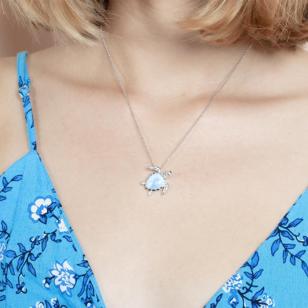 The picture shows a model wearing a 925 sterling silver larimar swimming sea turtle pendant.