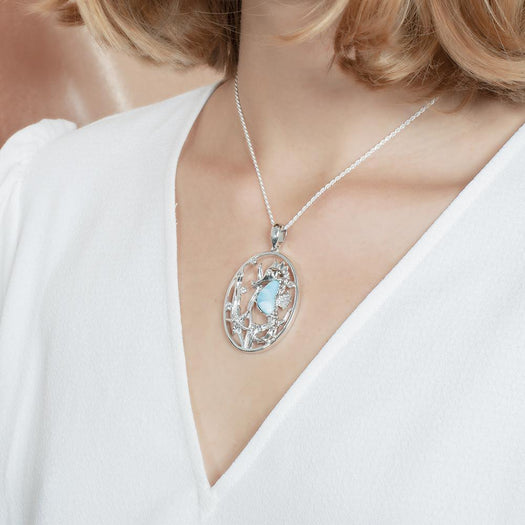 The picture shows a model wearing a 925 sterling silver pendant with a seahorse, starfish, and seaweed including a larimar gemstone and cubic zirconia.