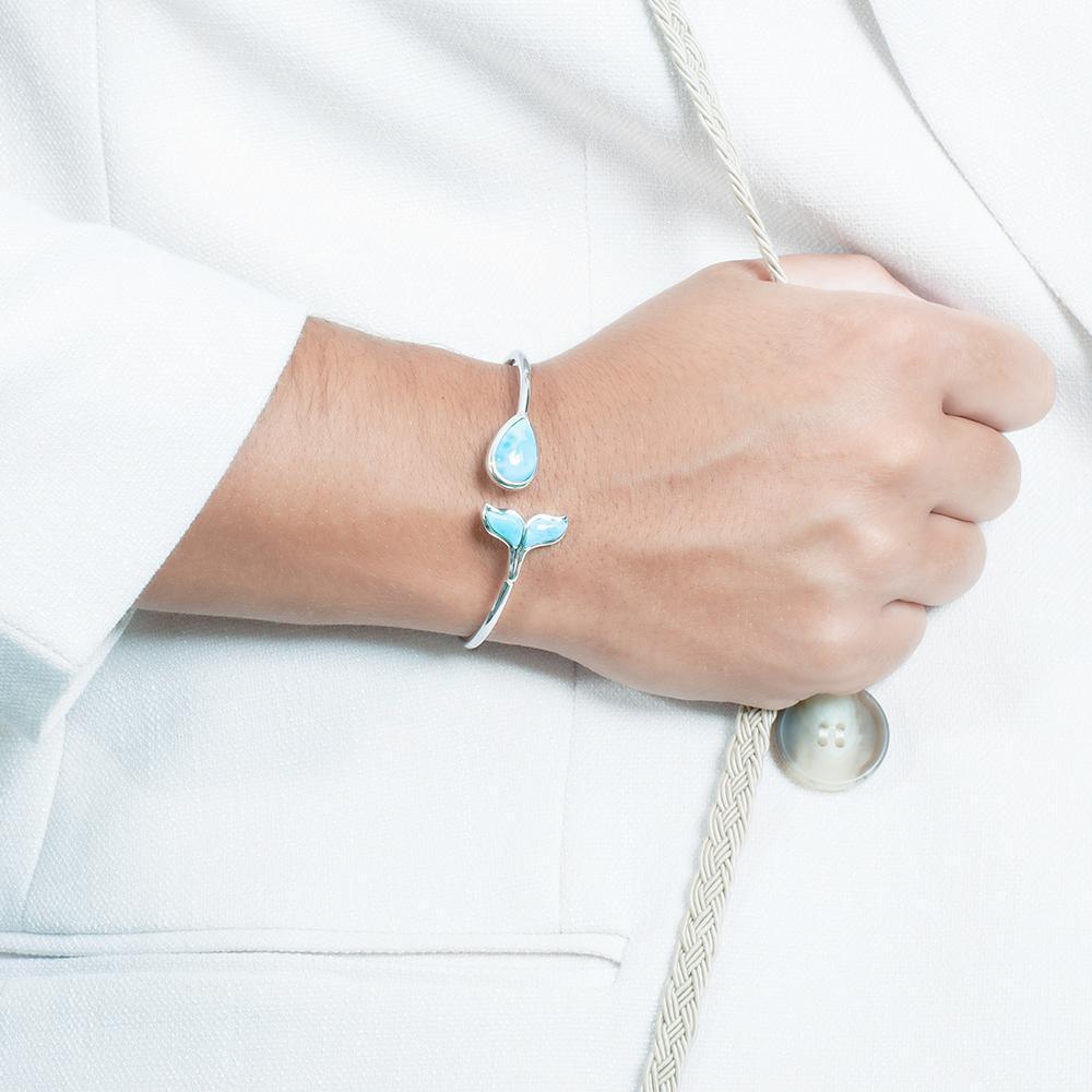 The picture shows a model wearing a 925 sterling silver larimar whale tail and teardrop bangle.