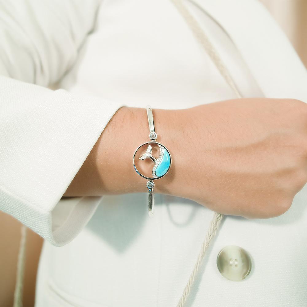 The picture shows a model wearing a 925 sterling silver larimar whale tail wave bracelet with topaz.