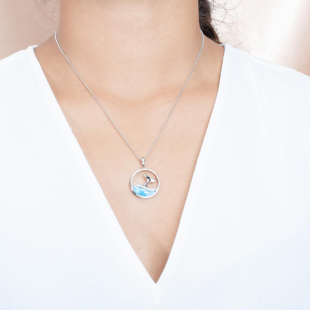 The picture shows a model wearing a 925 sterling silver larimar whale tail wave pendant with topaz.