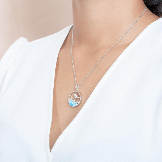 The picture shows a model wearing a 925 sterling silver larimar whale tail wave pendant with cubic zirconia.