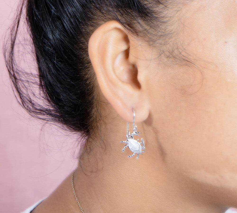 The picture shows a model wearing a 925 sterling silver blue crab hook earring.