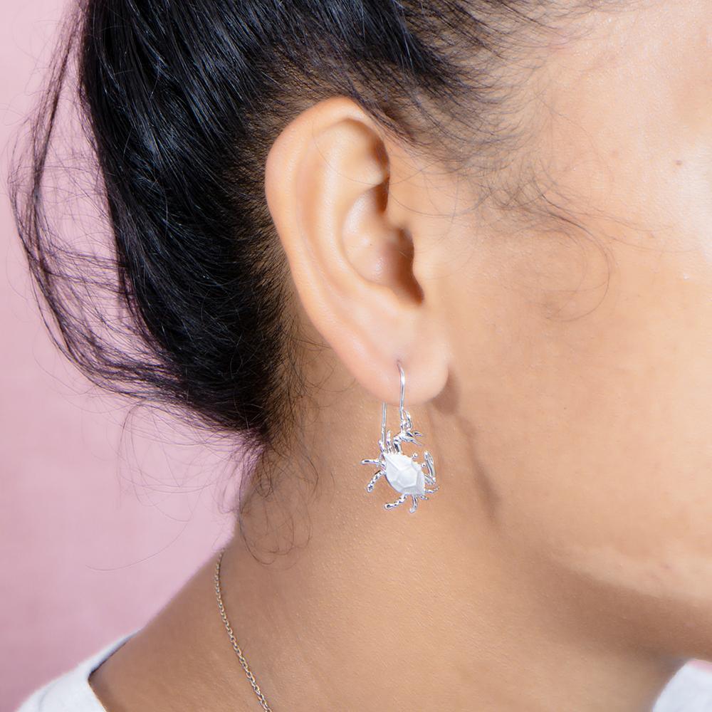 The picture shows a model wearing a 925 sterling silver blue crab hook earring.