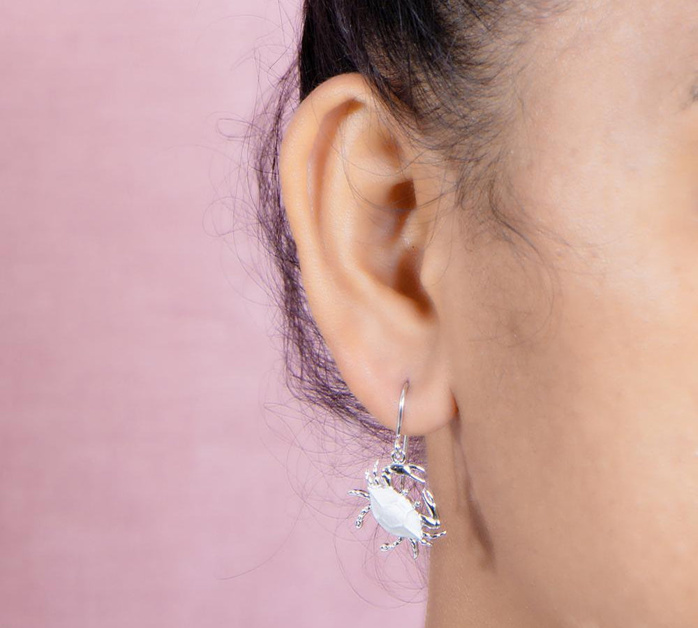 The picture shows a model wearing a 925 sterling silver blue crab hook earring.