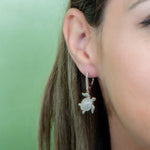 The picture shows a model wearing a 925 sterling silver sea turtle lever-back earring with topaz.