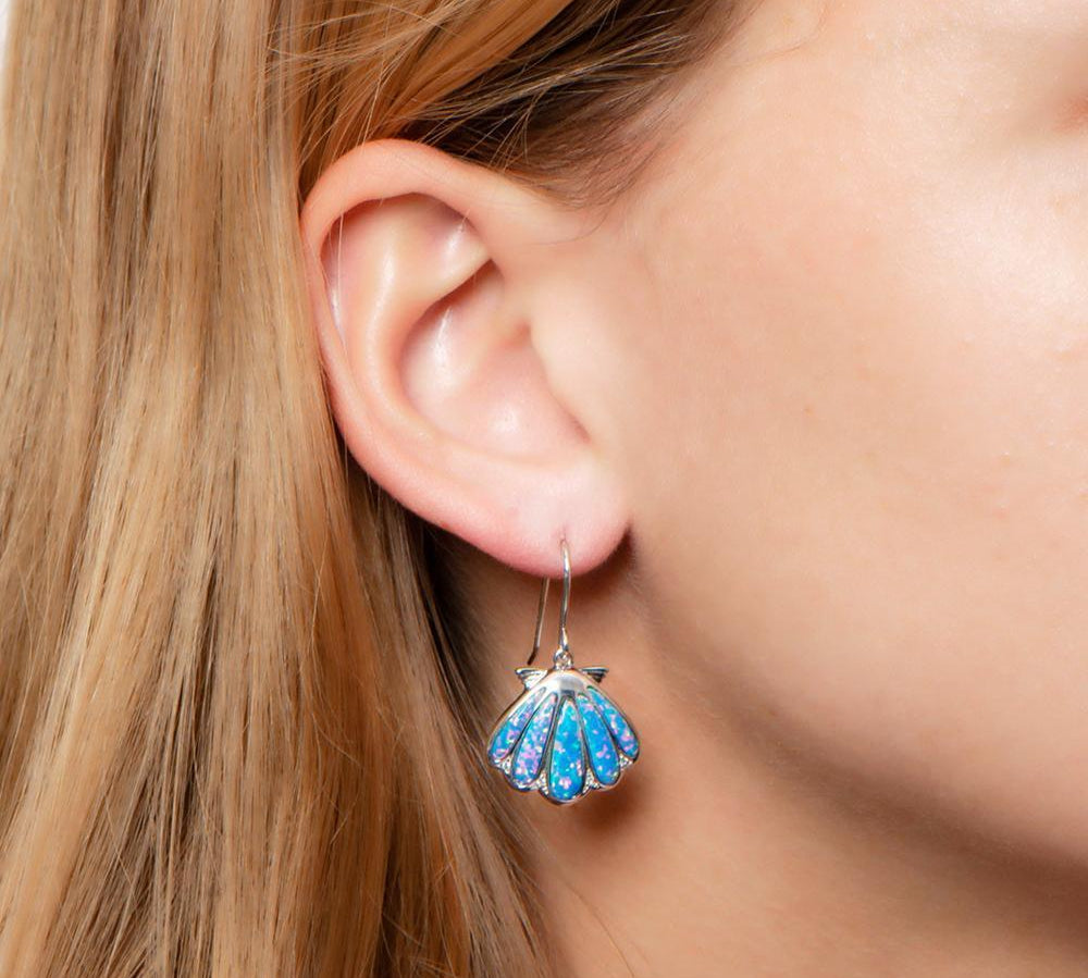 The picture shows a model wearing a 925 sterling silver opalite oyster shell hook earring with topaz