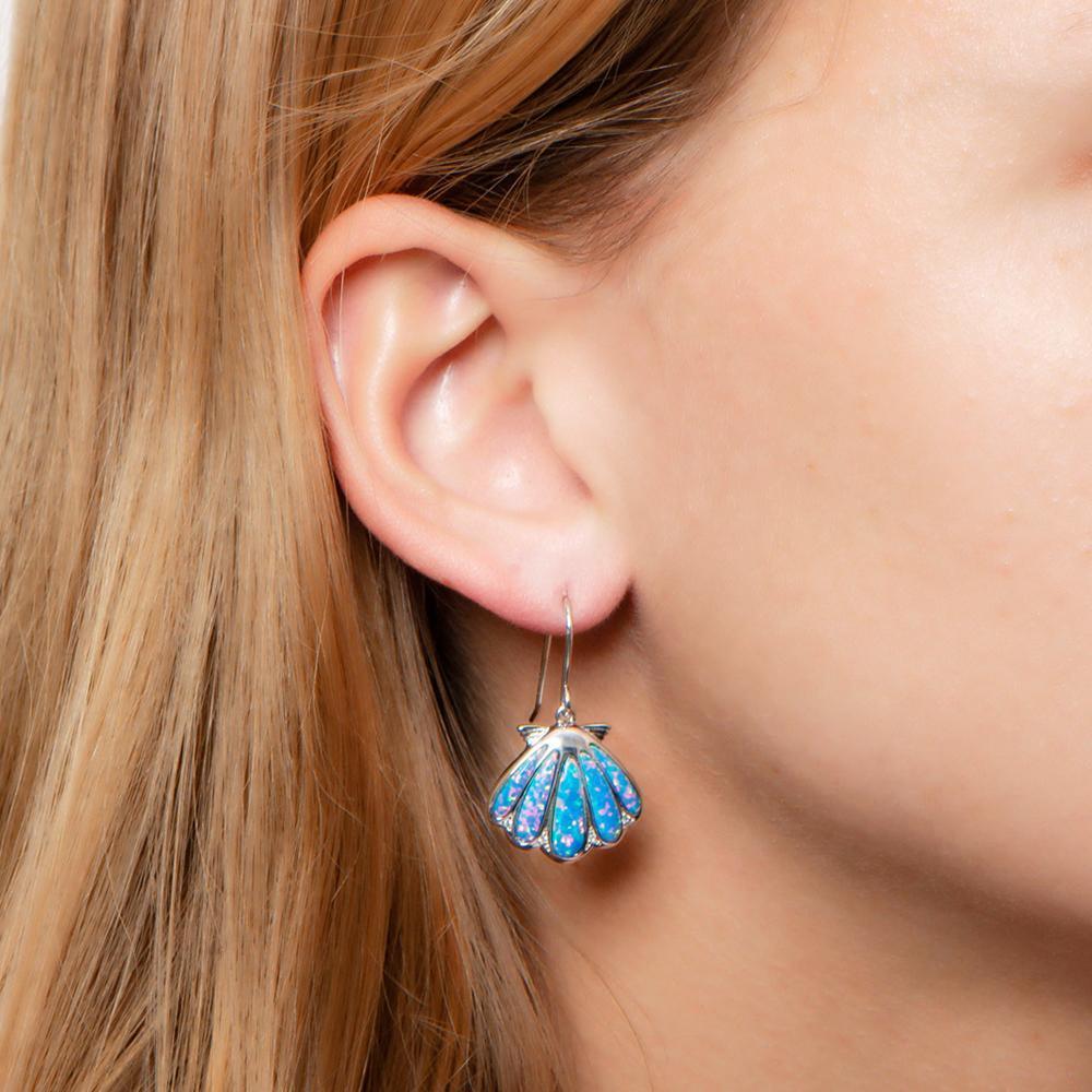 The picture shows a model wearing a 925 sterling silver opalite oyster shell hook earring with topaz