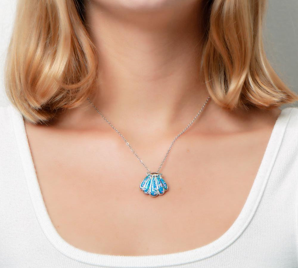 The picture shows a model wearing a 925 sterling silver oyster shell pendant with opalite and topaz.