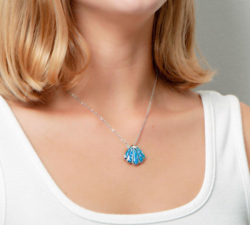 The picture shows a model wearing a 925 sterling silver oyster shell pendant with opalite and topaz.