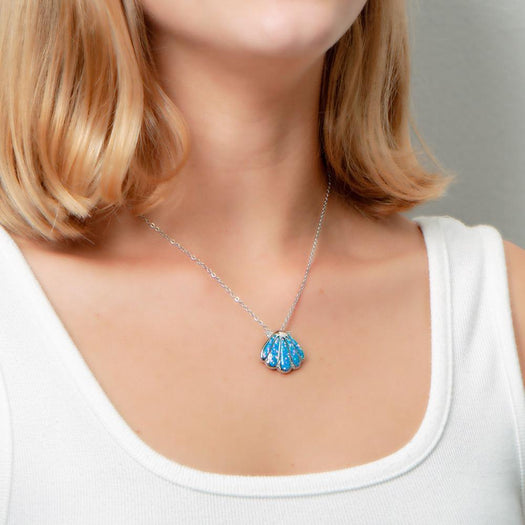 The picture shows a model wearing a 925 sterling silver oyster shell pendant with opalite and topaz.