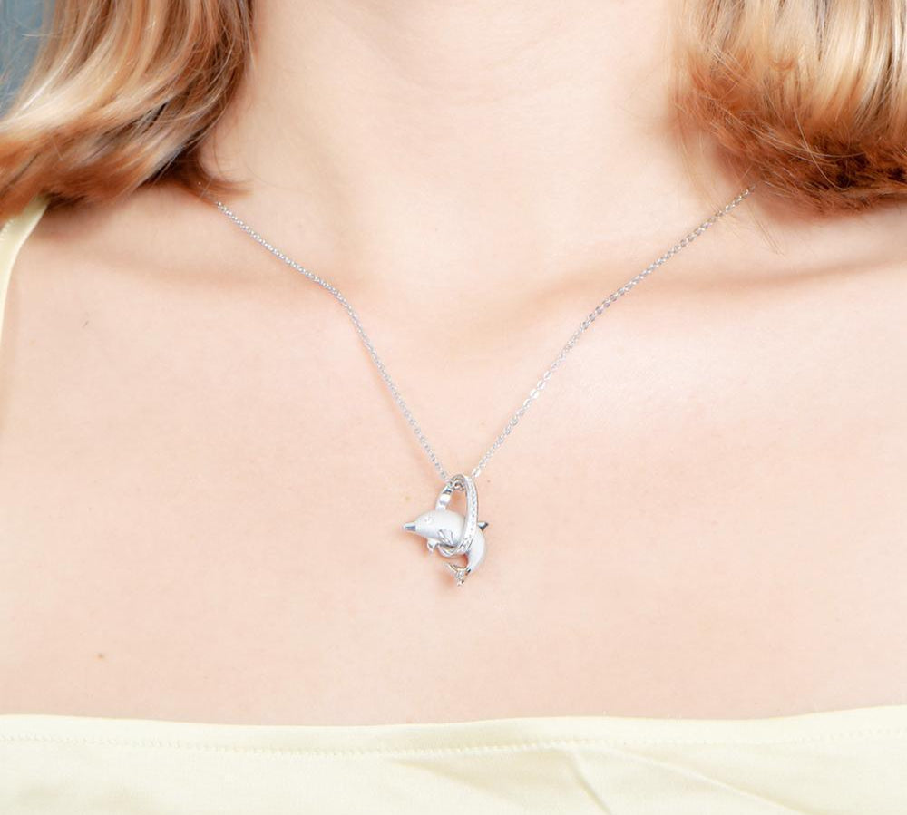 The picture shows a model wearing a 925 sterling silver dolphin through a circle pendant with topaz.