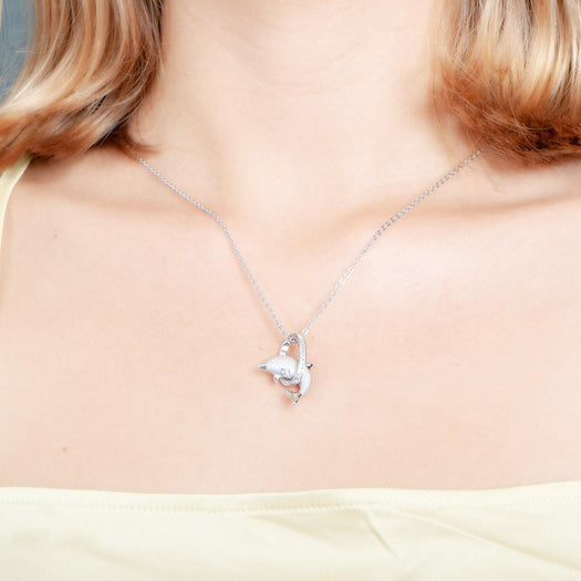 The picture shows a model wearing a 925 sterling silver dolphin through a circle pendant with topaz.