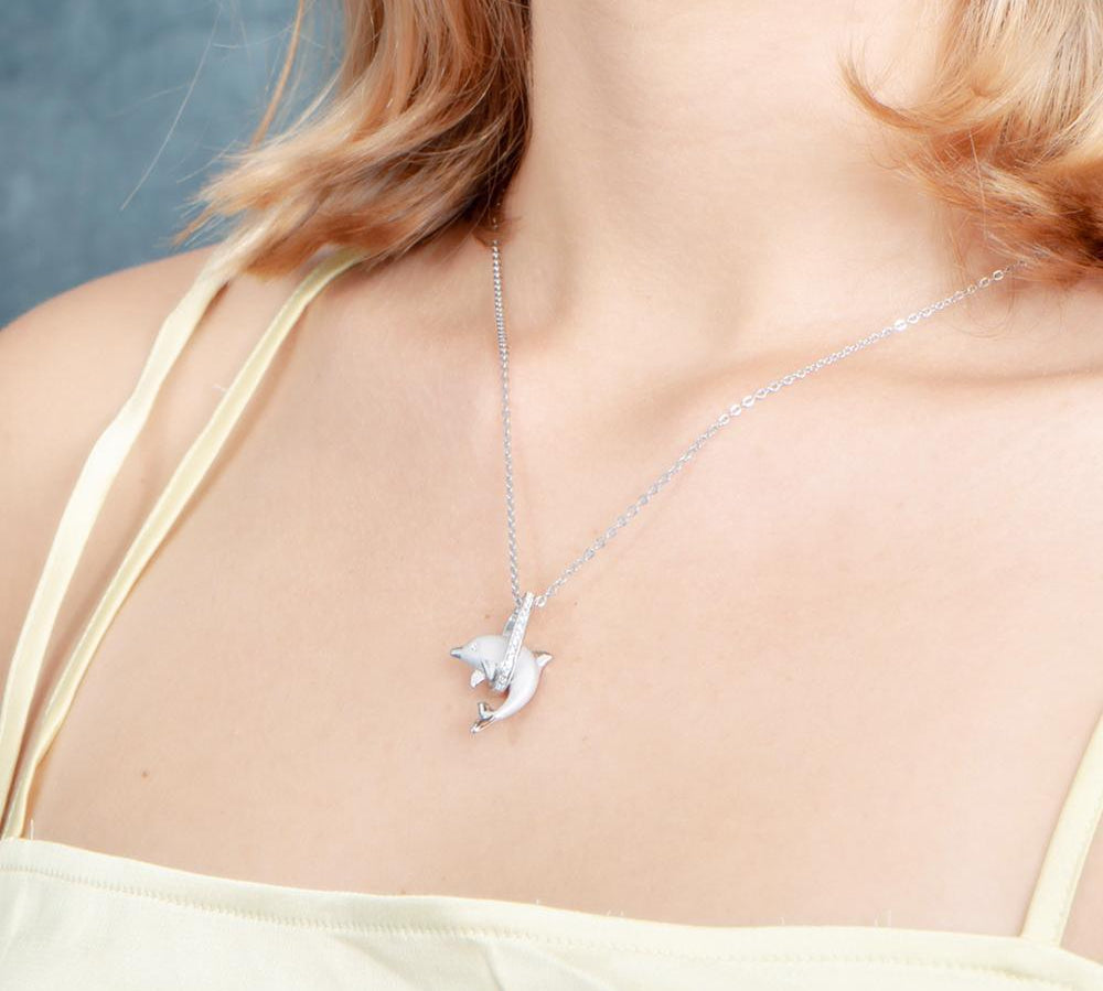 The picture shows a model wearing a 925 sterling silver dolphin through a circle pendant with  topaz.