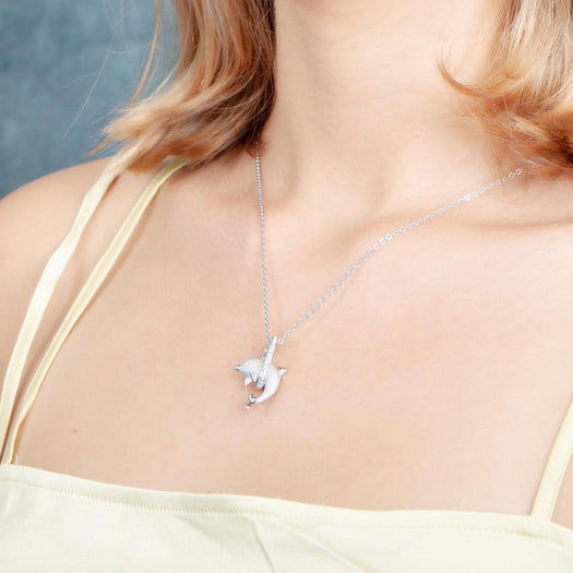 The picture shows a model wearing a 925 sterling silver dolphin through a circle pendant with  topaz.