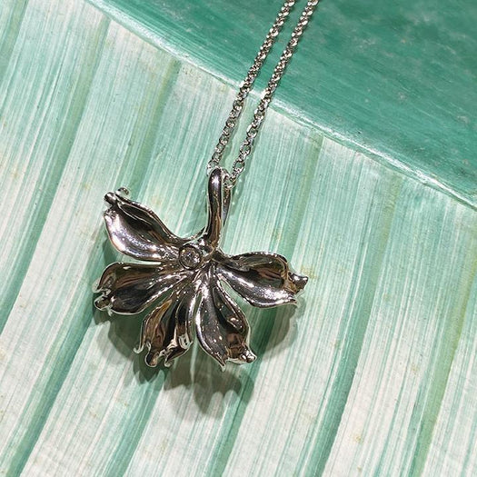 In this photo there is a white gold naupaka flower pendant with one diamond.