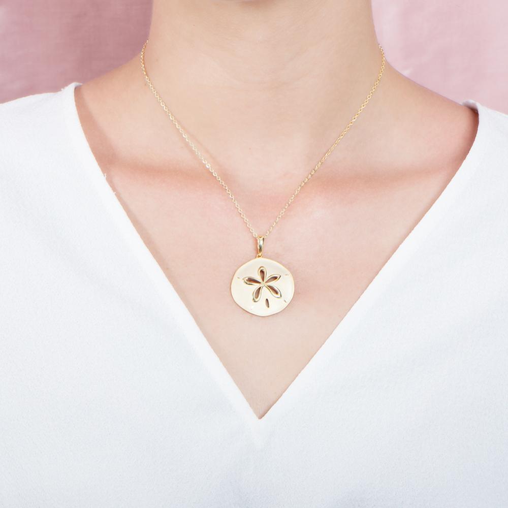 The picture shows a model wearing a 925 sterling silver, yellow gold plated, sand dollar cut out pendant with topaz.