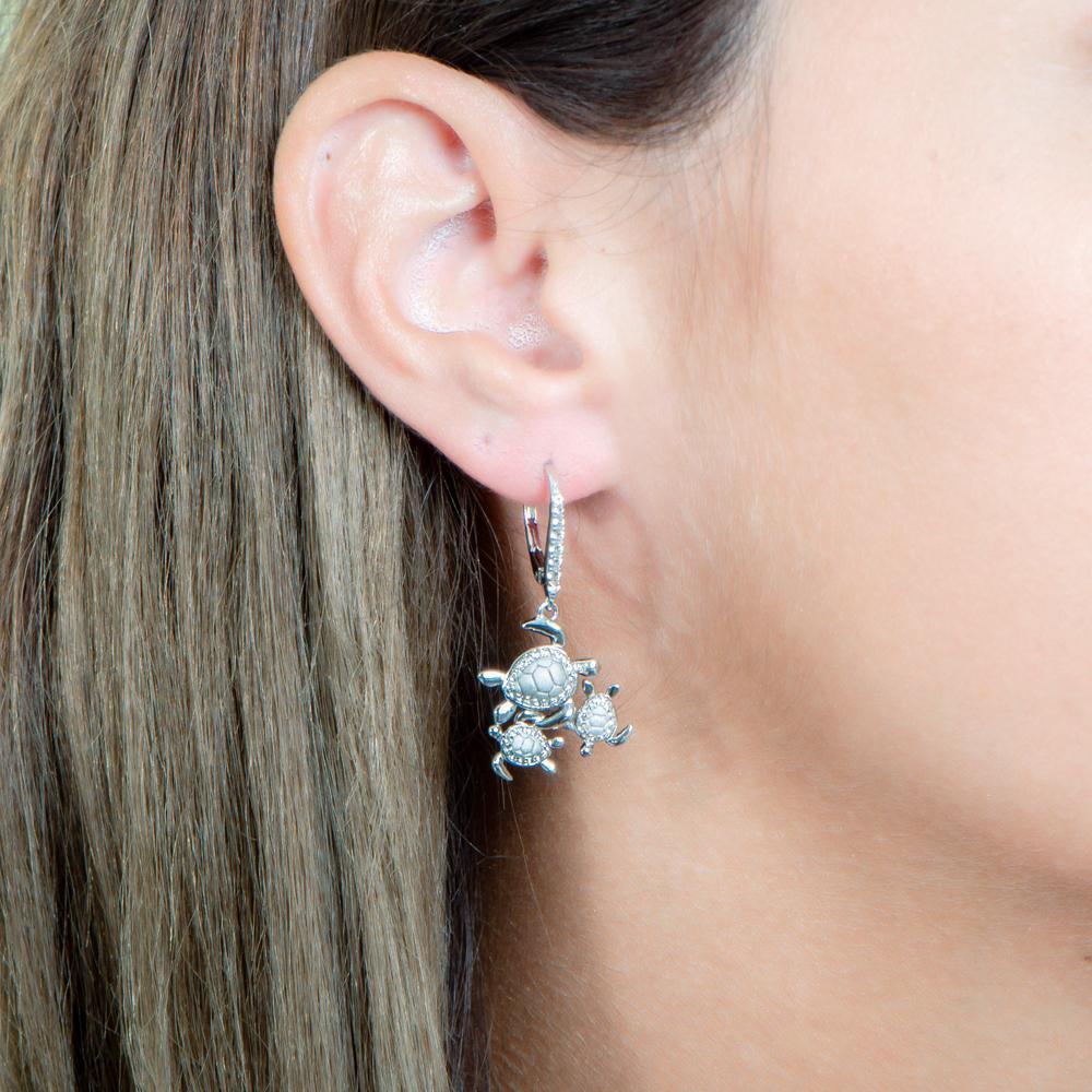 The picture shows a model wearing a 925 sterling silver three sea turtle earring with topaz.