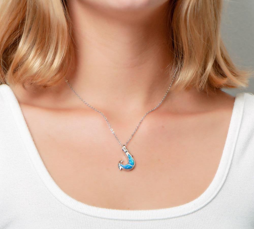 In this photo there is a model with blonde hair and a white shirt, wearing a sterling silver fish hook pendant with blue opalite gemstones.