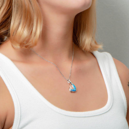 In this photo there is a model turned to the right with blonde hair and a white shirt, wearing a sterling silver fish hook pendant with blue opalite gemstones.