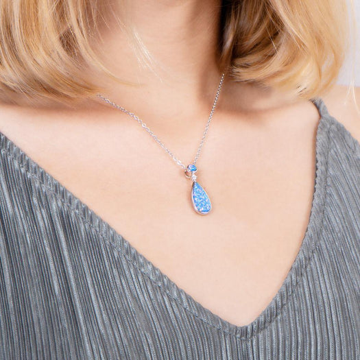 The picture shows a model wearing a 925 sterling silver opalite teardrop pendant with cubic zirconia.