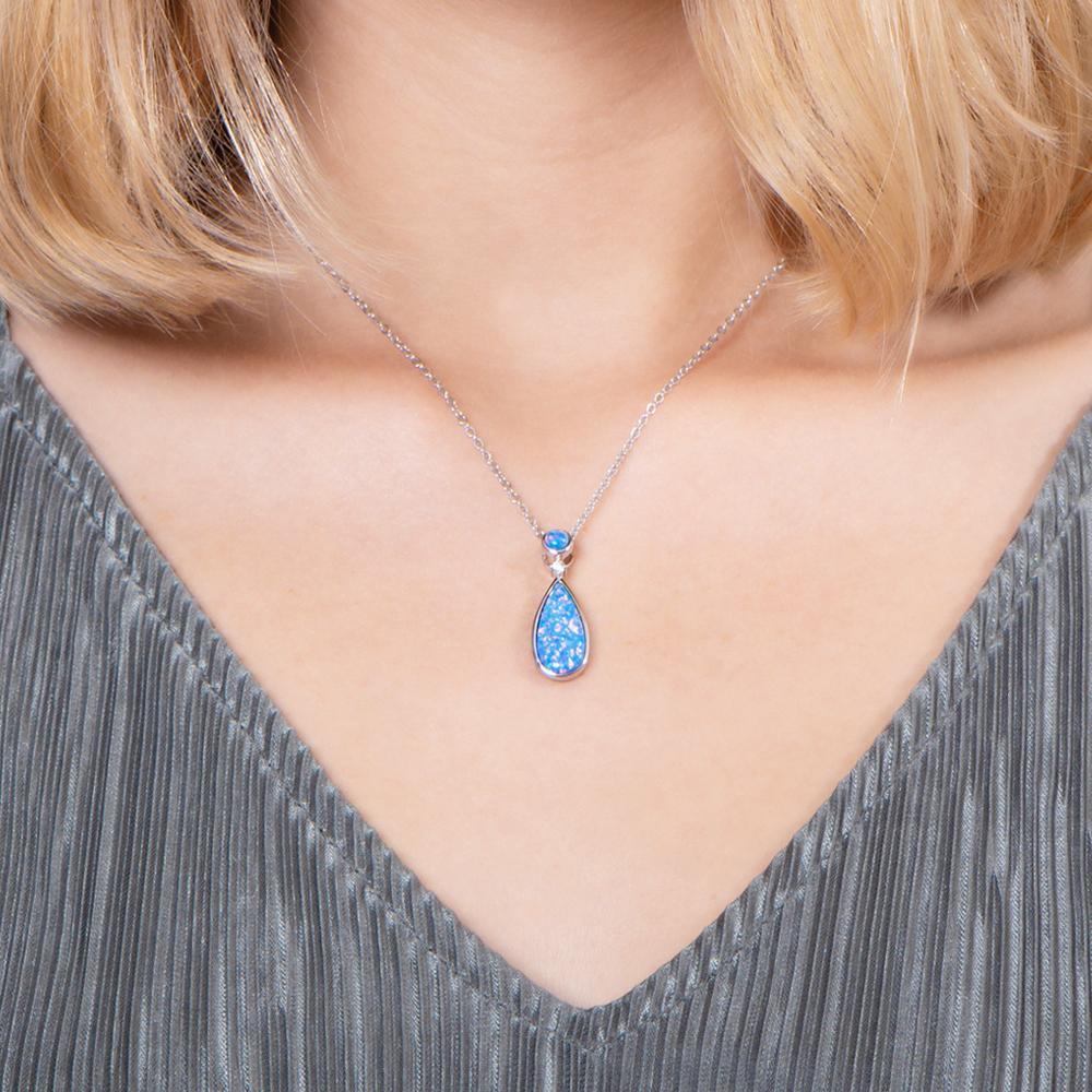 The picture shows a model wearing a 925 sterling silver opalite teardrop pendant with cubic zirconia.