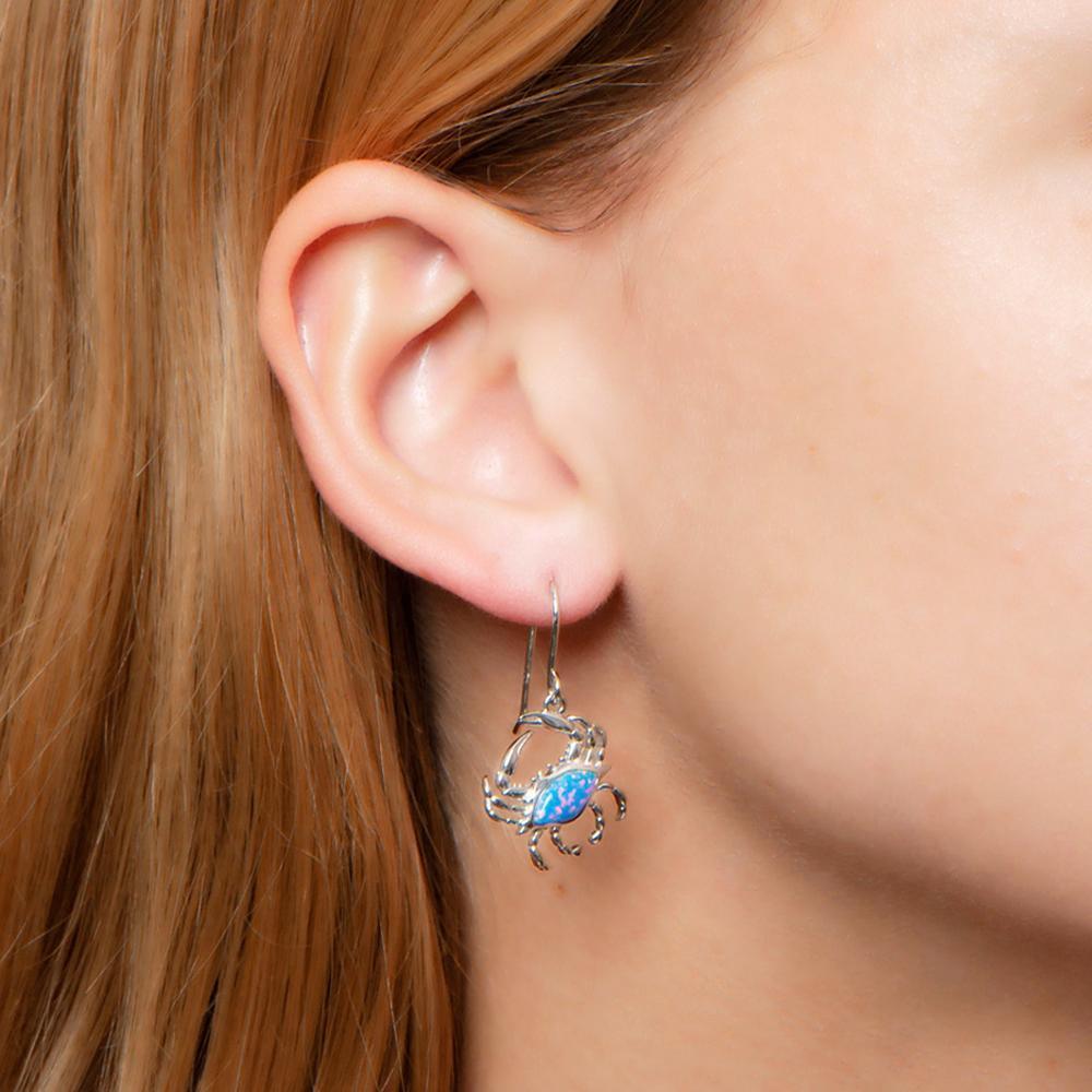 The picture shows a model wearing a 925 sterling silver opalite blue crab earring.
