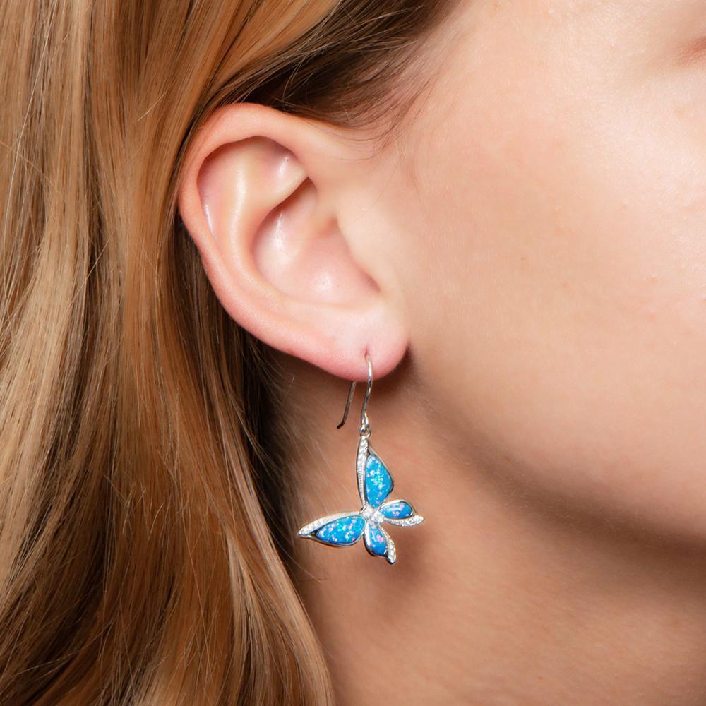 In this photo there is a model with strawberry blonde hair wearing sterling silver butterfly hook earrings with blue opalite gemstones and topaz.