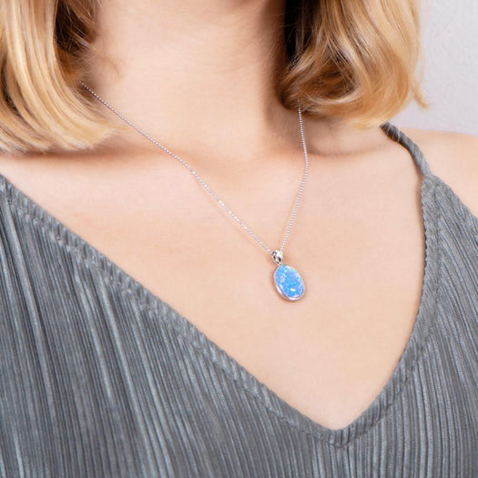 The photo shows a model wearing a sterling silver opalite full moon pendant with topaz. 