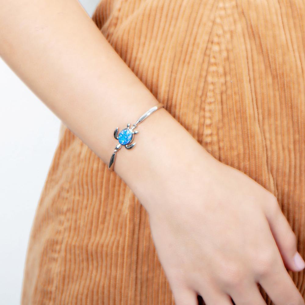 The picture shows a model wearing a 925 sterling silver opalite sea turtle bracelet.