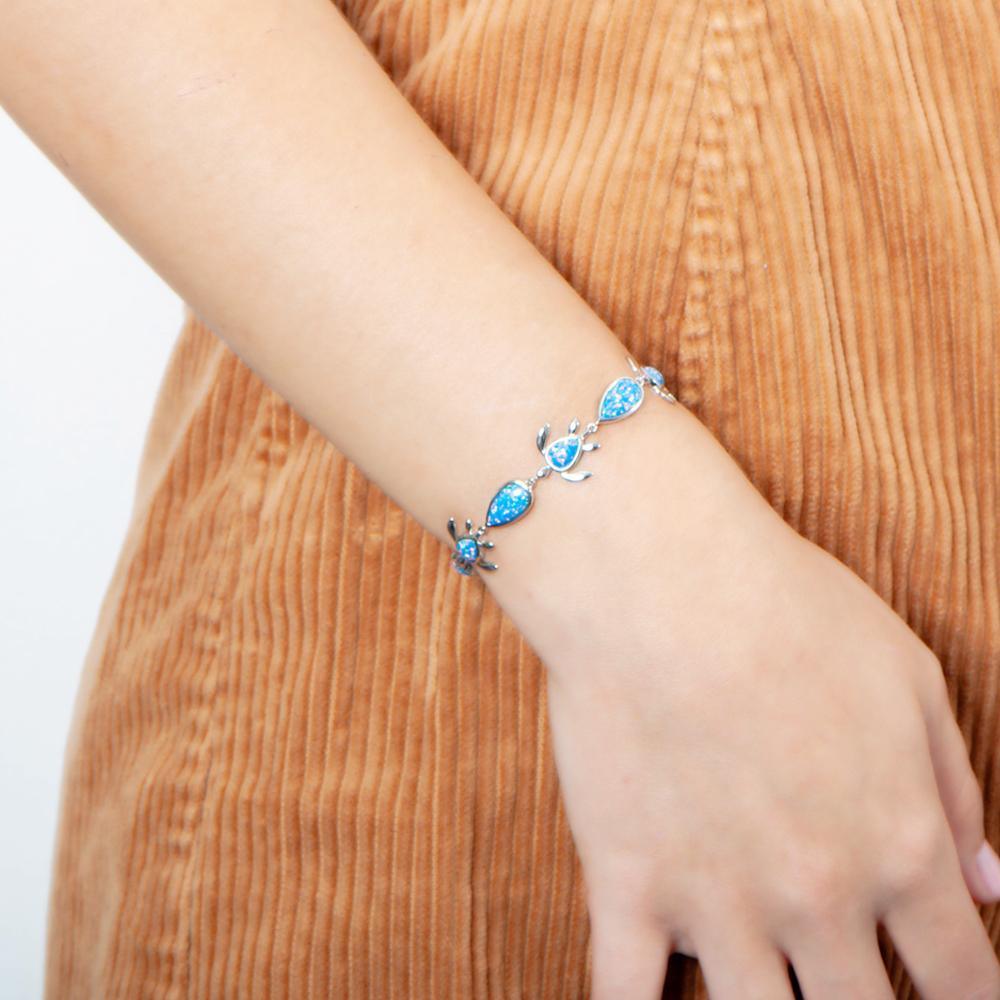 The picture shows a model wearing a 925 sterling silver opalite sea turtle and teardrop charm bracelet