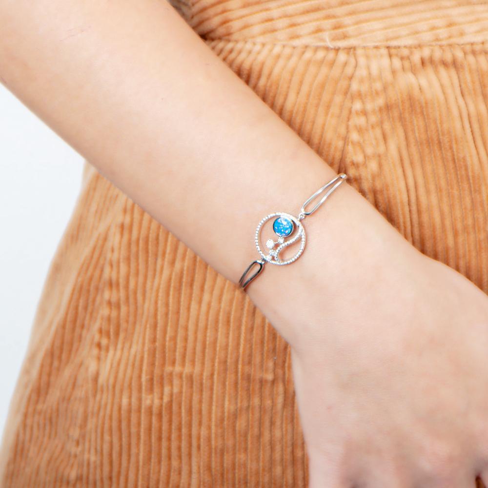 In this photo there is a model wearing a sterling silver wave and sun bracelet with blue opalite, aquamarine and topaz gemstones
