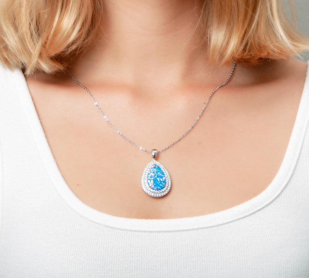 The picture shows a model wearing a 925 sterling silver opalite teardrop pendant with cubic zirconia.