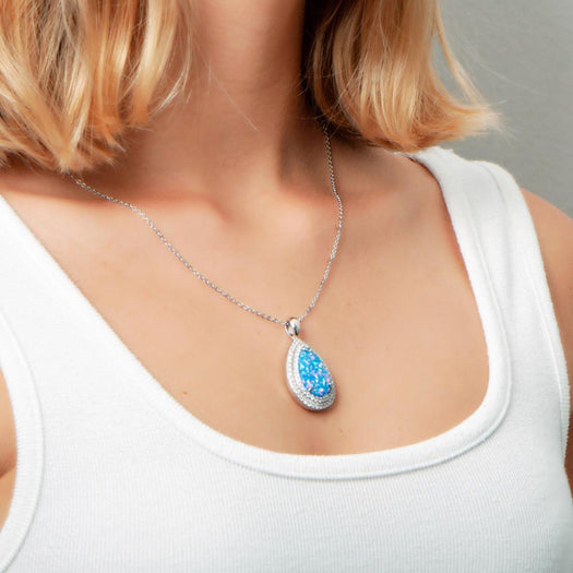 The picture shows a model wearing a 925 sterling silver opalite teardrop pendant with cubic zirconia. Pendant Island by Koa Nani