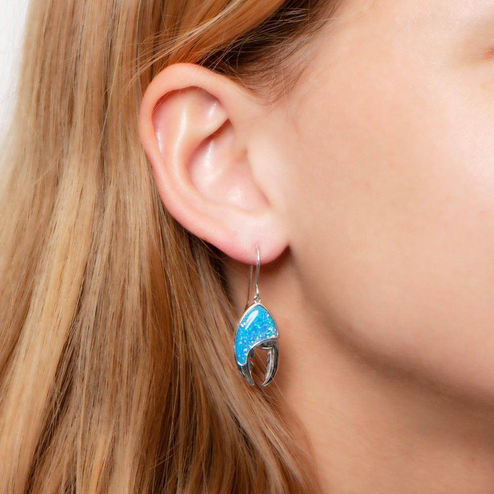 In this photo there is a close-up of a model with blonde hair wearing sterling silver lobster claw hook earrings with blue opalite gemstones.